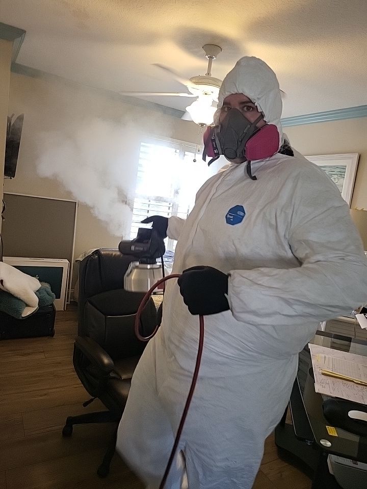 Technician in full PPE using thermal fogger to eliminate smoke odor in home office
